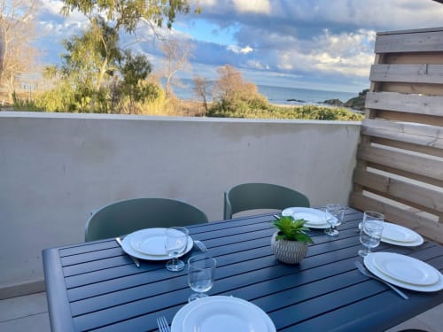Aménagement de table en bord de mer à la Résidence Marina di Bravone avec vue sur la mer, couverts et paysage côtier à Linguizzetta,