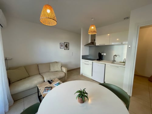 Appartement moderne à la Résidence Marina di Bravone avec séjour ouvert, cuisine, table ronde et luminaires en suspension tressés