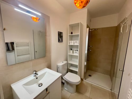 Bagno moderno della Résidence Marina di Bravone con lavandino, WC, doccia walk-in e scaffali in Linguizzetta