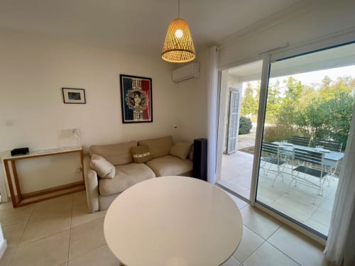 Accogliente appartamento T2 presso Résidence Marina di Bravone, Linguizzetta con divano beige, tavolo rotondo e accesso alla terrazza