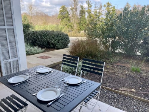 Terrazza pranzo esterna a Marina di Bravone con tavolo preparato, sedie nere e vista sul giardino a Linguizzetta, Corsica