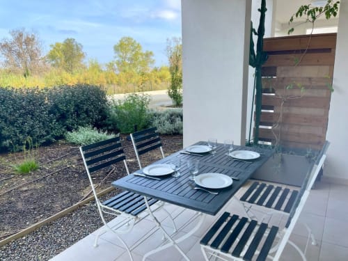 Zona pranzo esterna a Marina di Bravone con tavolo apparecchiato, sedie e vista sul giardino a Linguizzetta