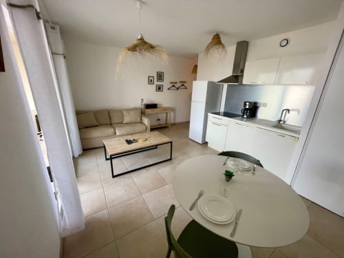 Open-plan apartment at Résidence Marina di Bravone with dining area, lounge, and white kitchen overlooking beachfront in