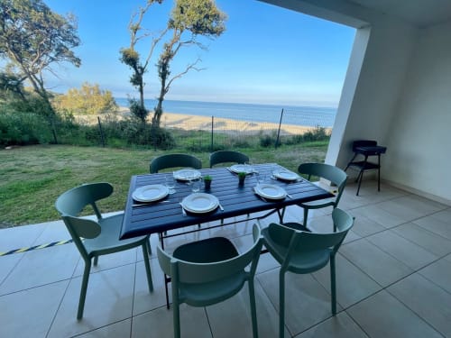 Terrasse de l'appartement en bord de mer à la Résidence Marina di Bravone, Linguizzetta, avec table de repas donnant sur la plage et la mer