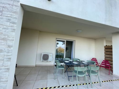Covered terrace at Résidence Marina di Bravone with dining table, mint chairs, sea view, and air conditioning unit