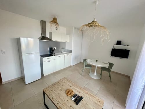 Modern beachfront T3 apartment at Résidence Marina di Bravone with open kitchen, dining area, and natural fiber pendant