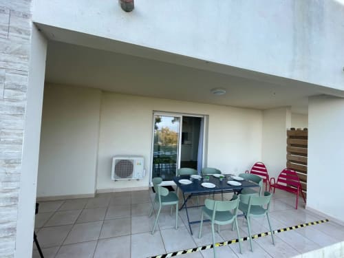Beachfront apartment dining area at Résidence Marina di Bravone with table, green chairs, and sea view