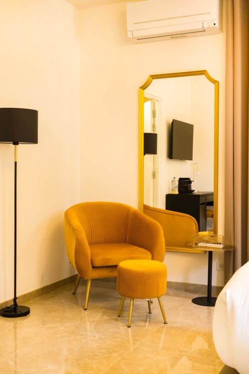 Poltrona dorata e poggiapiedi con lampada da terra e specchio da toeletta nella suite deluxe dell'Hotel Villa Martini, Ajaccio