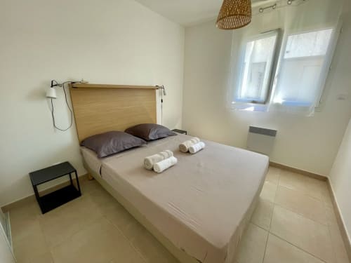 Chambre épurée à la Résidence Marina di Bravone avec lit à tête de lit en bois, serviettes roulées et vue sur mer à Linguizzetta