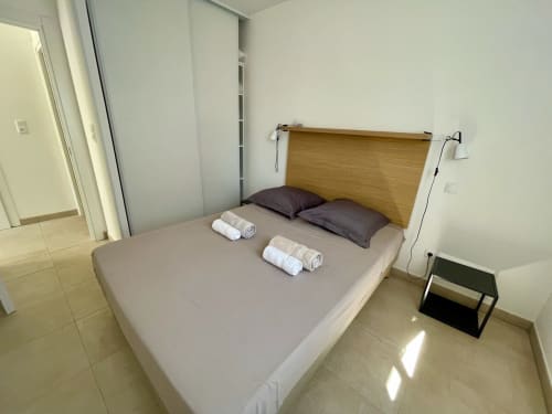 Chambre moderne à la Résidence Marina di Bravone avec tête de lit en bois, lits jumeaux, serviettes blanches et armoires coulissantes