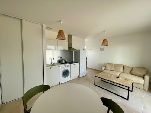 Appartement moderne à la Résidence Marina di Bravone avec cuisine ouverte, salle à manger et canapé beige à Linguizzetta