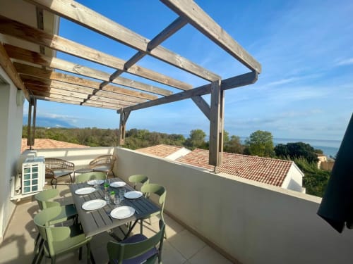 Terrasse panoramique de la Résidence Marina di Bravone avec table à manger, vue sur mer et pergola en bois à Linguizzetta, Corse