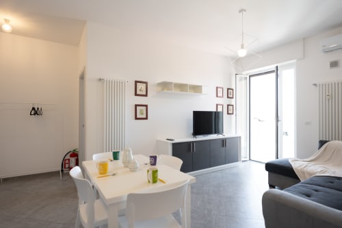 Elegante zona living con tavolo da pranzo, TV a schermo piatto e vista mare al Welcome Holiday, Finale Ligure