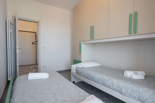 Camera da letto moderna con letti gemelli nell'appartamento Maestrale a Varigotti, con accenti verdi e vista sul mare