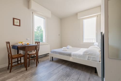 Camera moderna e luminosa dell'Hotel Prince Garda a Solarolo con letto, tavolo da pranzo e accesso alla terrazza