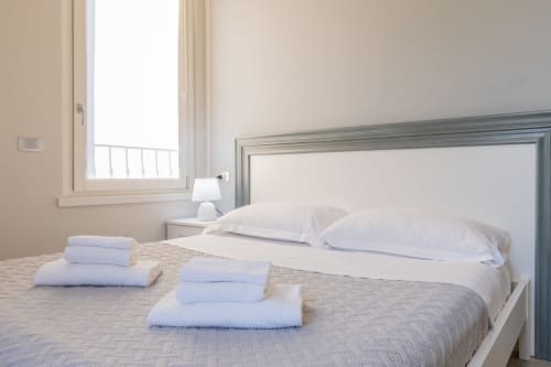 Camera luminosa dell'hotel Prince Garda a Solarolo con letto rifatto, cuscini bianchi, asciugamani blu ripiegati e luce naturale
