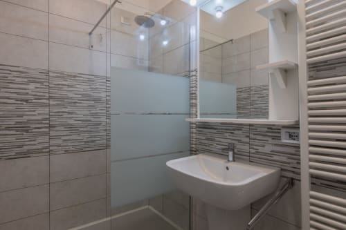 Bagno moderno dell'hotel Prince Garda a Solarolo con doccia walk-in, rivestimento a piastrelle righe, scaldariscaldamani e lavabo