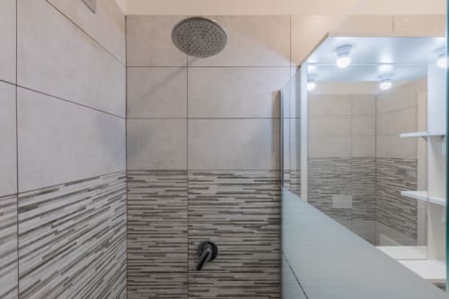 Moderno box doccia dell'hotel Prince Garda a Solarolo con soffione pioggia e rivestimenti in piastrelle a righe