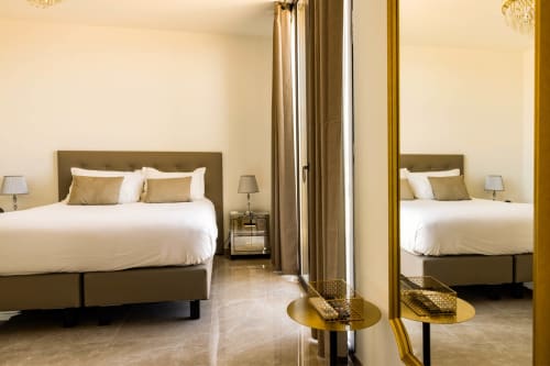 Esclusiva camera Deluxe all'Hôtel Villa Martini di Ajaccio con vista sul mare, letto king size, specchio dorato e raffinati arredi beige