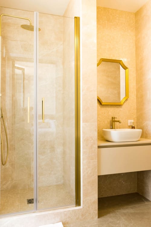 Bagno di lusso all'Hôtel Villa Martini Ajaccio con doccia in vetro, lavabo bianco, rubinetteria dorata e specchio decorativo