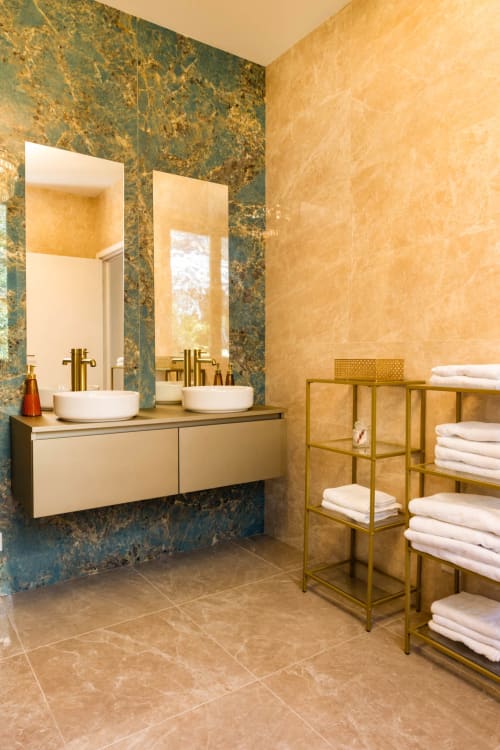 Lussuoso bagno dell'Hôtel Villa Martini, Ajaccio, con pareti in marmo, doppi lavabi, rubinetteria in ottone e scaffalature per asciugamani