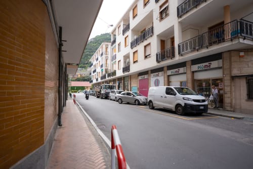 Vista stradale dell'appartamento Welcome Holiday a Varigotti con auto parcheggiate e negozi sotto l'edificio residenziale