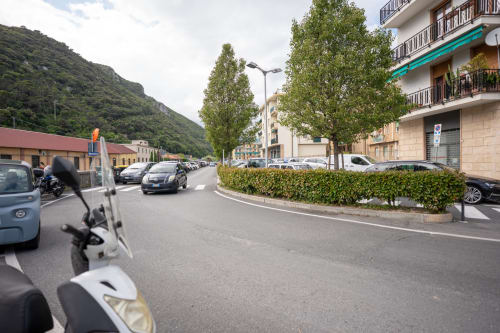 Veduta stradale del Welcome Holiday a Varigotti con auto parcheggiate, alberi verdi ed edifici immersi nel verdeggiante pendio