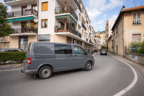 Furgone grigio parcheggiato in strada a Varigotti, Finale Ligure, con affascinanti edifici colorati e vista sul Mediterraneo