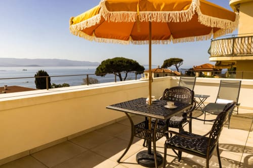 Terrazza privata con vista sul mare presso l'Hôtel Villa Martini, Ajaccio con mobili da pranzo e ombrellone giallo