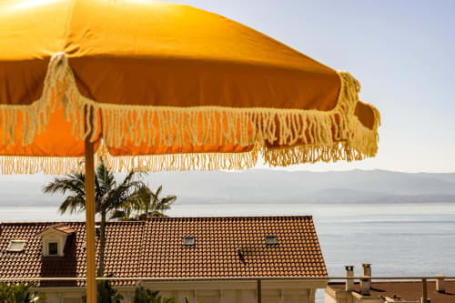 Terrazza di lusso dell'Hôtel Villa Martini ad Ajaccio con ombrellone a frangia gialla che si affaccia sul mare e le montagne della Corsica