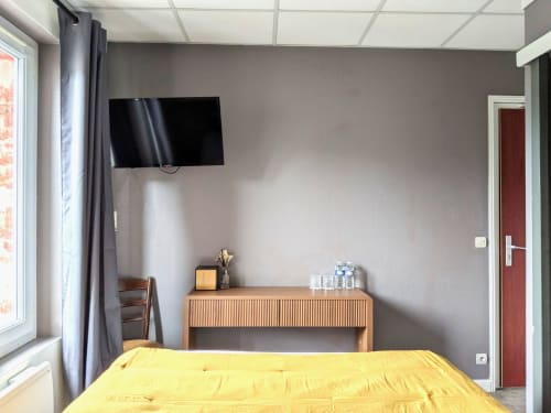 Chambre d'hôtel lumineuse aux Maisons Delphine avec literie jaune, télévision murale, bureau en bois et murs gris à Villers-sur-Mer