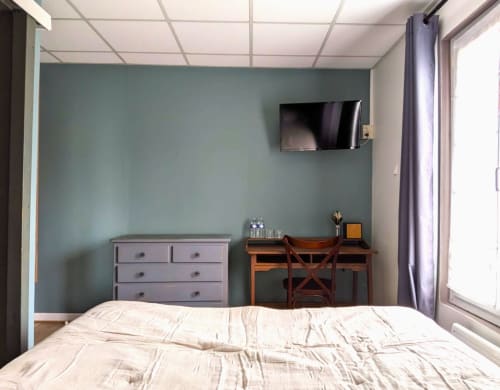 Chambre moderne du gîte Maisons Delphine avec lit, commode, bureau, TV murale et mur d'accent teal