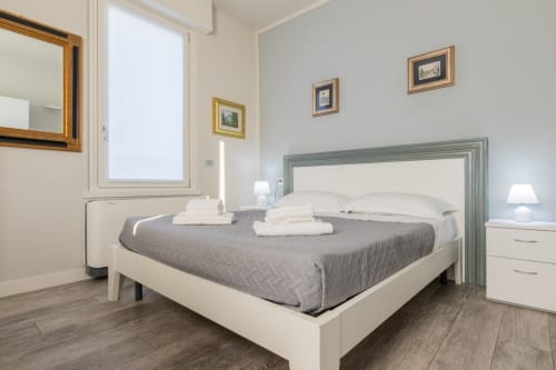 Camera moderna e luminosa dell'hotel Prince Garda a Solarolo con letto queen, testata grigia e comodini bianchi