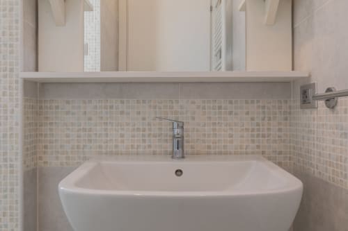 Moderno lavabo del bagno con rivestimento in piastrelle a mosaico presso l'hotel Prince Garda di Solarolo
