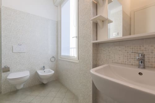 Bagno moderno a Prince Garda con piastrelle mosaico bianche, lavandino, WC, bidet e finestra a Solarolo