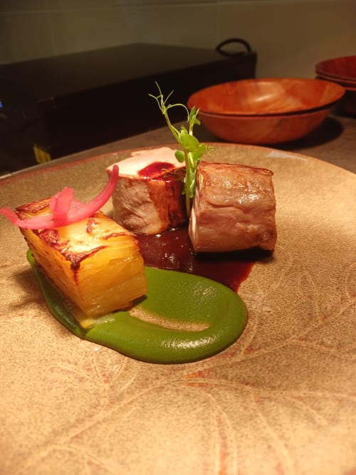 Gourmet plated dish at Clos De La Gourmandiere with seared foie gras, braised meat, and green sauce garnish