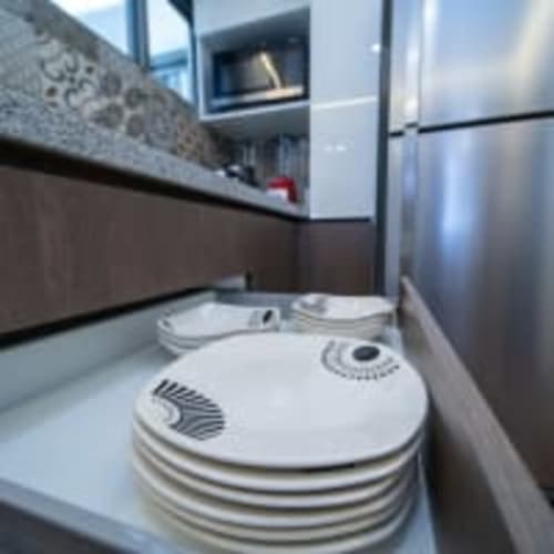 Cocina moderna en Apartamentos Posada Country, Guadalajara con electrodomésticos de acero inoxidable y platos apilados en la encimera