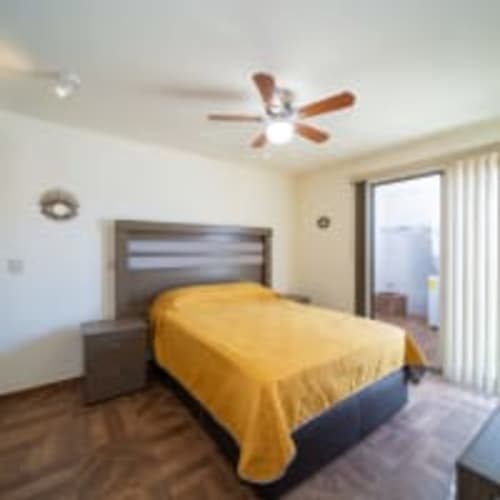 Habitación moderna en Apartamentos Posada Country, Guadalajara con colcha amarilla, ventilador de techo y balcón con vista a la ciudad