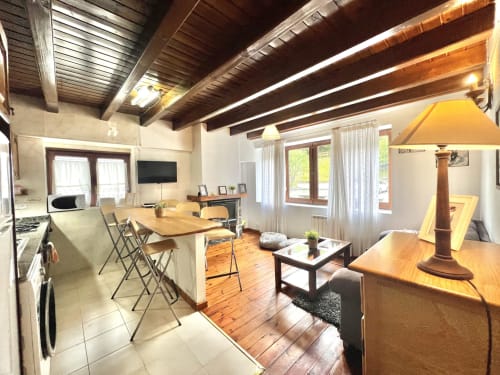 Moderno apartamento diáfano en Vielha con vigas de madera, cocina, comedor, salón con TV y vistas a la montaña
