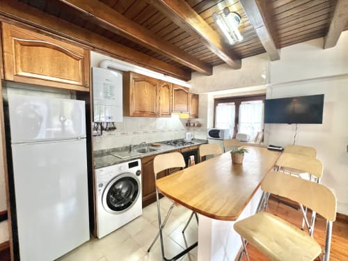 Cocina y comedor modernos del apartamento Eth Cauba en Vielha, con vigas de madera, electrodomésticos y mesa de madera