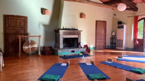 Yogastudio bij Podere di Maggio met blauwe matten, open haard en houten balken in Santa Fiora