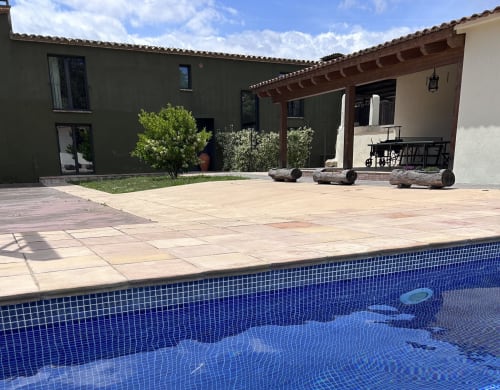 Piscina de l'hotel Mas Escarrà amb rajoles blaves, terrassa de pedra i arquitectura moderna a Caldes de Malavella