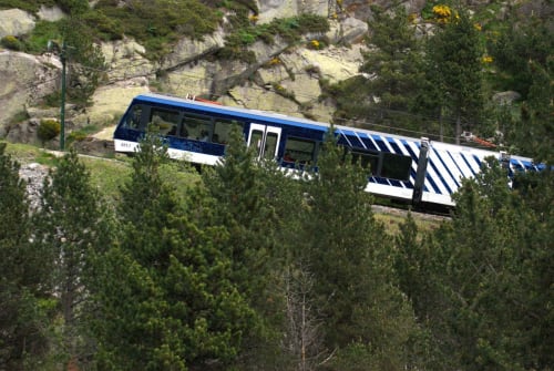 Teleférico de montaña con librea azul y blanca cerca de Campelles, Girona, rodeado de pinos y terreno rocoso