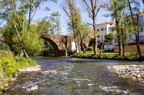 Ponte de pedra sobre rio com árvores na quinta SOTAM Country House, um encantador refúgio de hospedagem em Góis, Portugal
