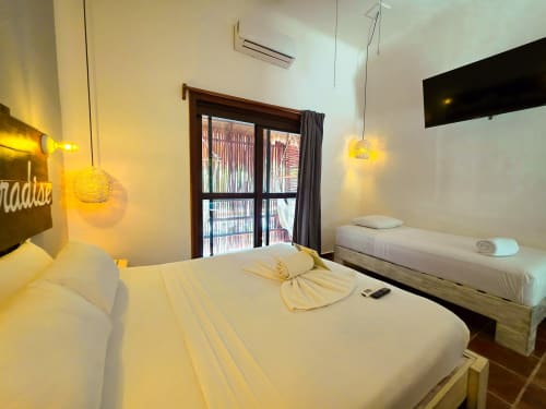 Moderna habitación del Hotel 40 Cañones en Mahahual con camas gemelas, lámparas colgantes amarillas y balcón con vistas