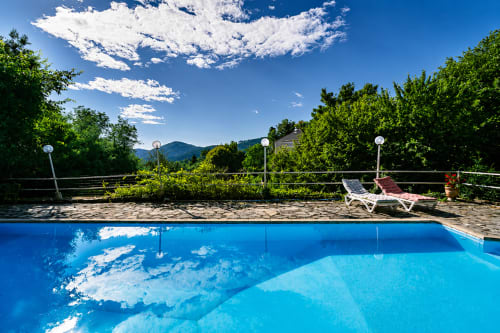 Piscine bleu cristal du Domaine de Cabrières à Saint-Jean-du-Gard, avec transats et vue sur les montagnes