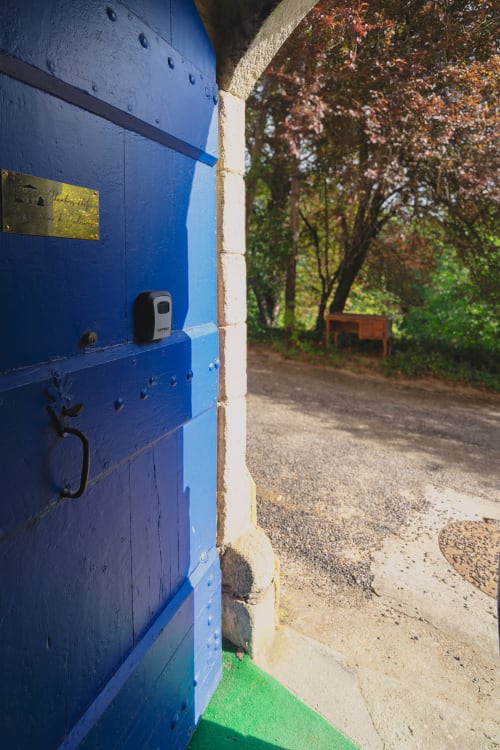 Bright blue door at Domaine de Cabrières B&B in St Jean Du Gard with garden view and trees beyond