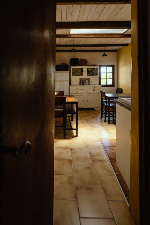 Cuisine rustique au Domaine de Cabrières avec poutres apparentes, armoires crème et carrelage terre cuite à St Jean Du