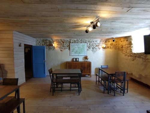 Salle à manger rustique du gîte Domaine de Cabrières à Saint-Jean-du-Gard avec tables en bois, murs en pierre et éclairage chaleureux