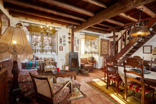 Sala de estar rústica com vigas de madeira, lareira, mobiliário tradicional e piso em terracota na SOTAM Country House